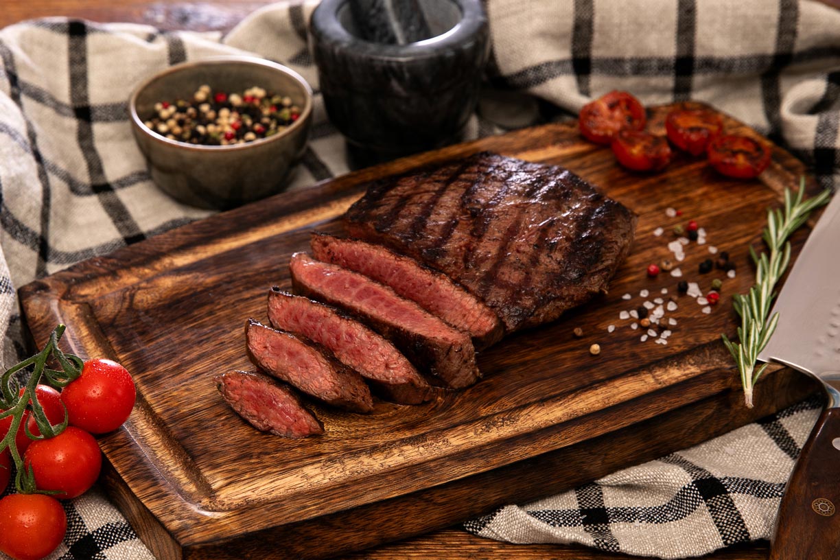 Gegrilltes deutsches Wagyu Flat Iron Steak, medium rare aufgeschnitten auf einem Holzbrett